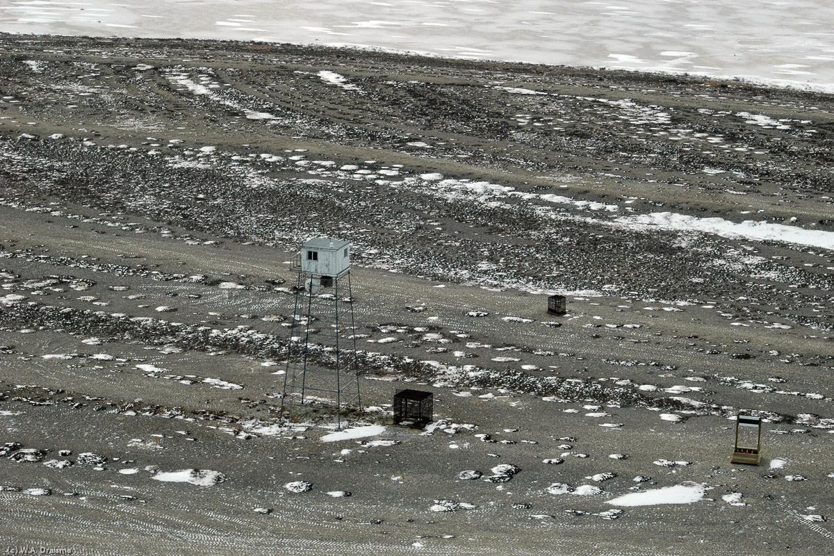 Below us the terrain is coloured black and white with little other colours. A lone watchtower is the only signal of human presence in this barren landscape.