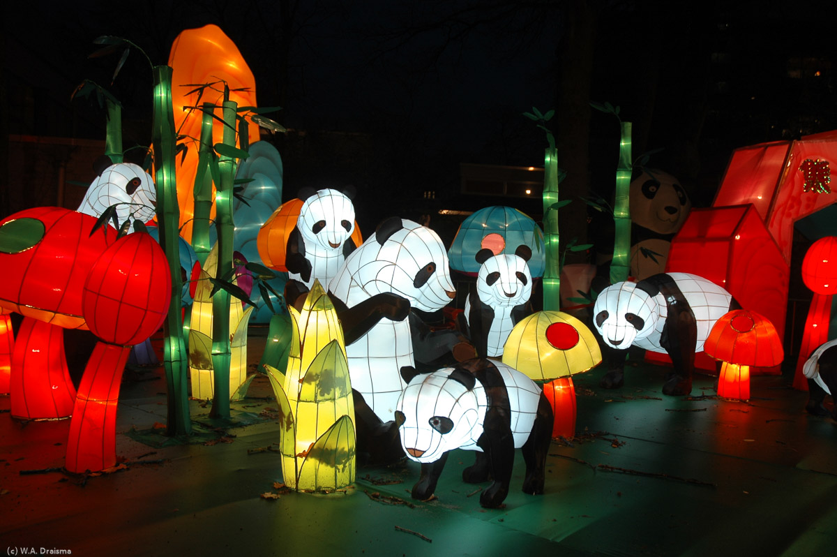 A total of six panda bears are visible while a seventh one rides around in a cart.