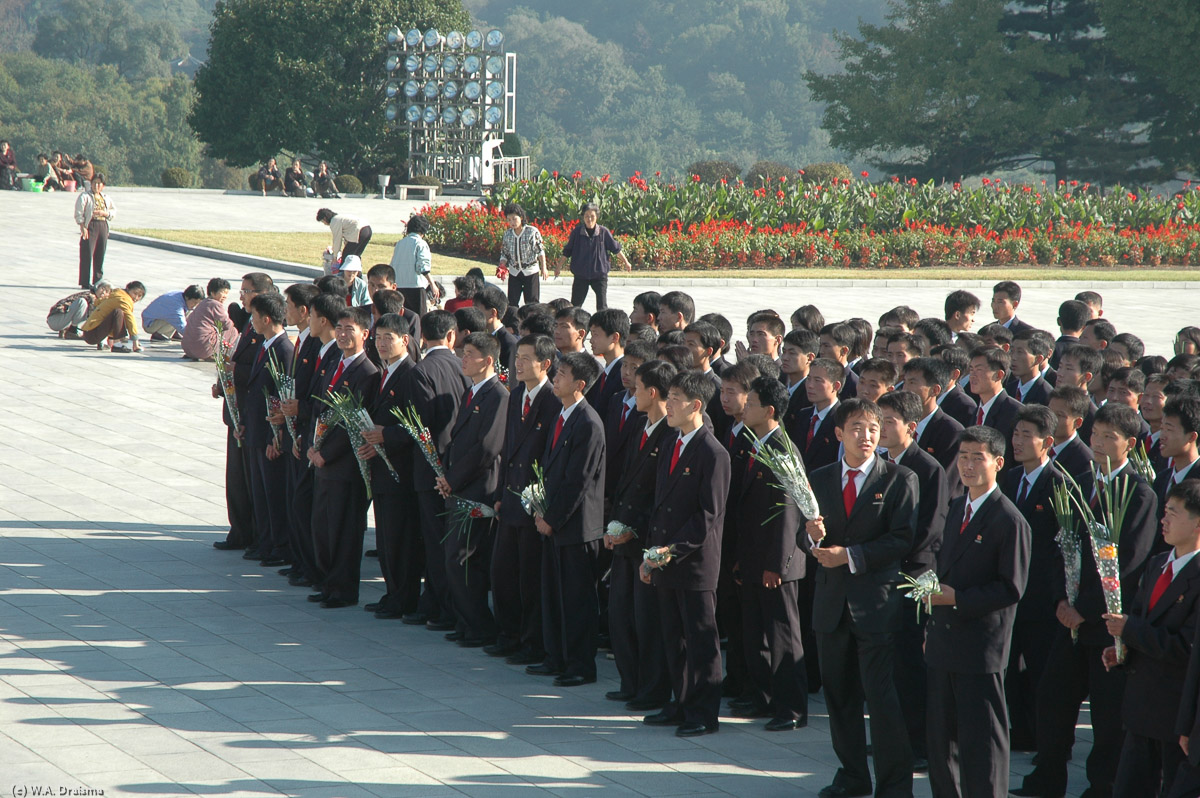 Students, dressed in their best suits wait for their turn to show their respect to Kim Il Sung. Our turn also comes. And after a solemn bow we also lay a bouquet at the Eternal President's feet.