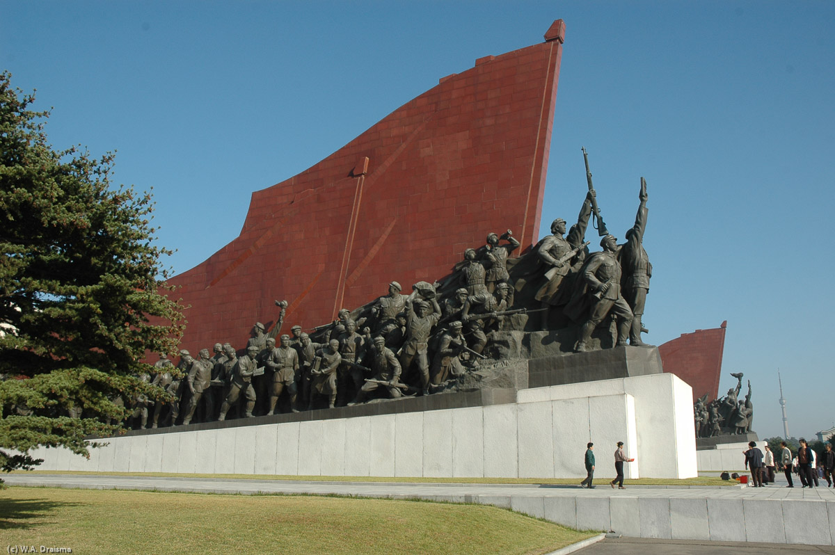The Great Leader is flanked by two flags carved from stone and lined with hundreds of bronze figures. The group on the left is called "Anti-Japanese Revolutionary Struggle".