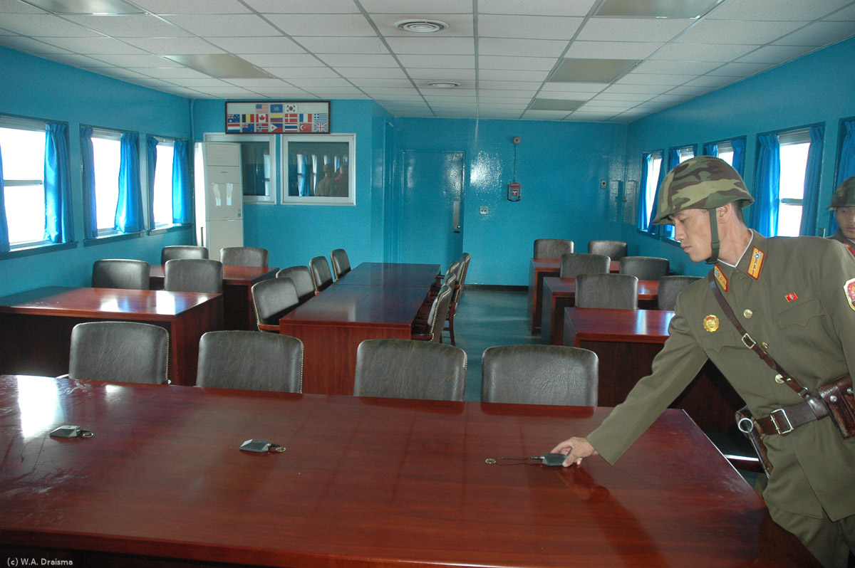The conference table is right on the border and the microphone cable marks the exact borderline. In the back the flags of the 13 countries that joined the UN forces in the Korean War.