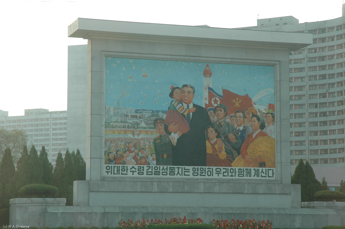 Driving on Thongil Street, a monolithic housing development, a mural indicating that "The Great Leader Comrade Kim Il Sung will be with us forever".