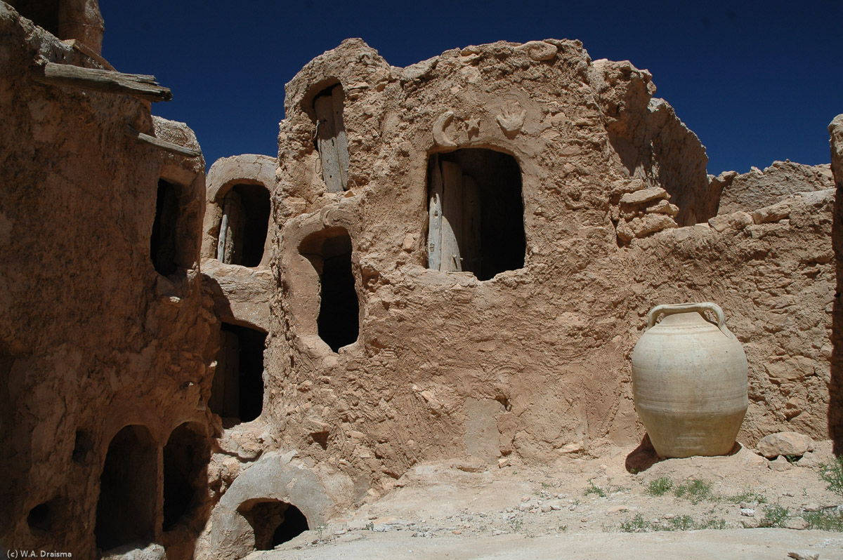 The qasr's interior is strewn with old pieces of pottery one used to store dates, wheat, oil and barley. Many of the rooms, of which the last ones fell in disuse in 1960, are still closed by palm-trunk doors. Several also show inscriptions like the crescent moon, a start and the hand of Fatima.