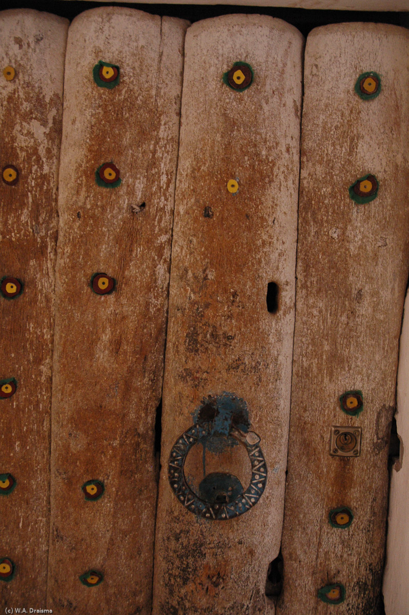 Most of the Ghadames doors are made of palm trunks split in two to form planks. Every now and then, a door is decorated by small leather studs in bright red, green and yellow (the colours of Ghadames indicating that the owner of the house has made the haj pilgrimage to Mecca.