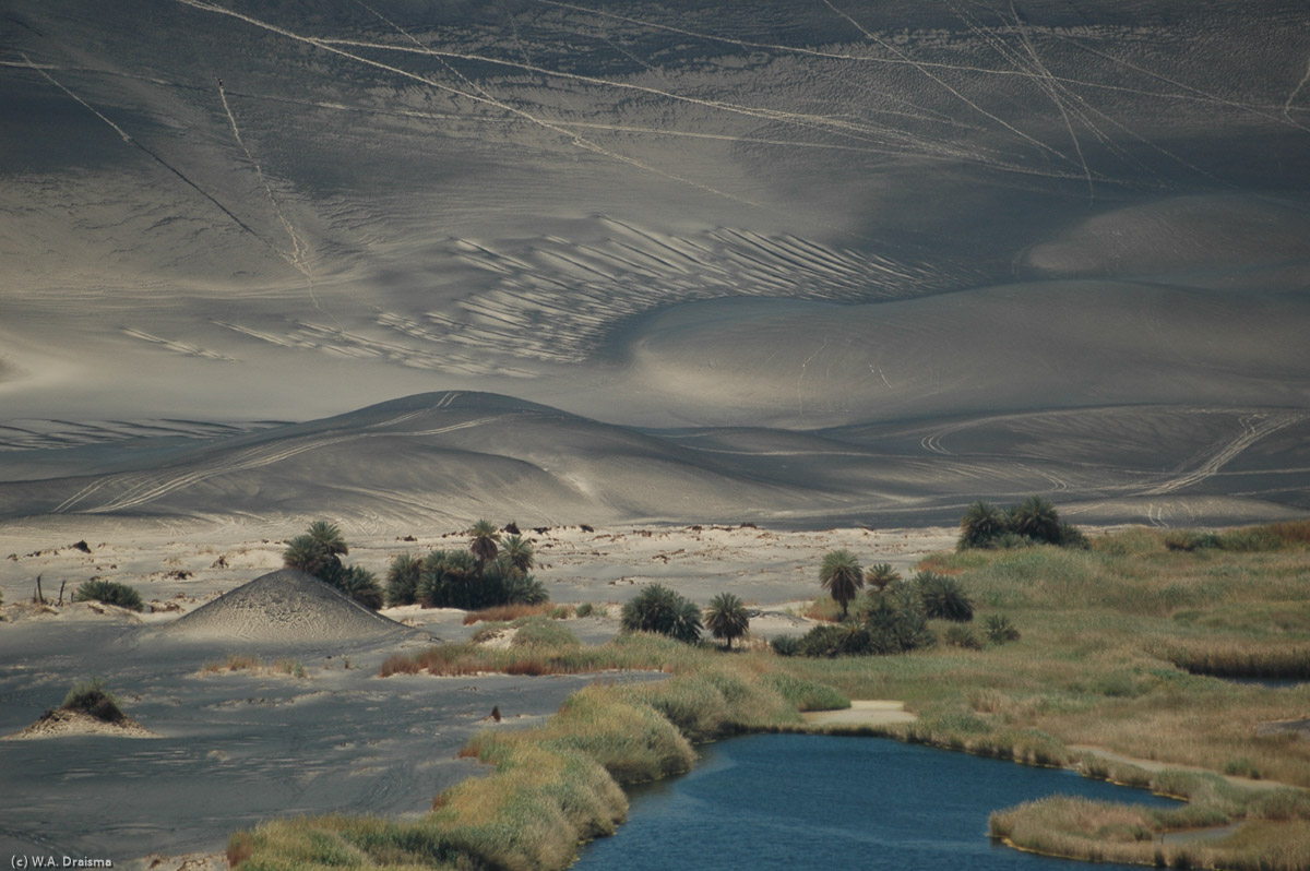 The now-extinct volcano of Waw an Namus is surrounded by three beautiful lakes, a blue one, a red one and a green one, each surrounded by high reeds and fine black and white volcanic sand.