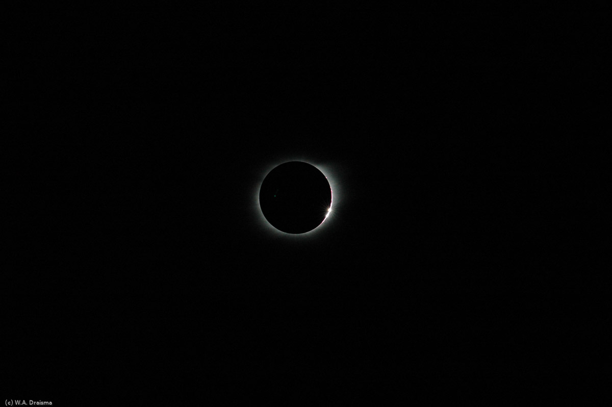 After 4 minutes of darkness, illuminated only by the sun's corona and some red prominences, huge flames of hot gas that radiate outward from the sun's surface, hundreds of thousands of kms long, the sun reemerges from behind the moon shining through valleys on the moon's surface at first: Bailey's Beads.