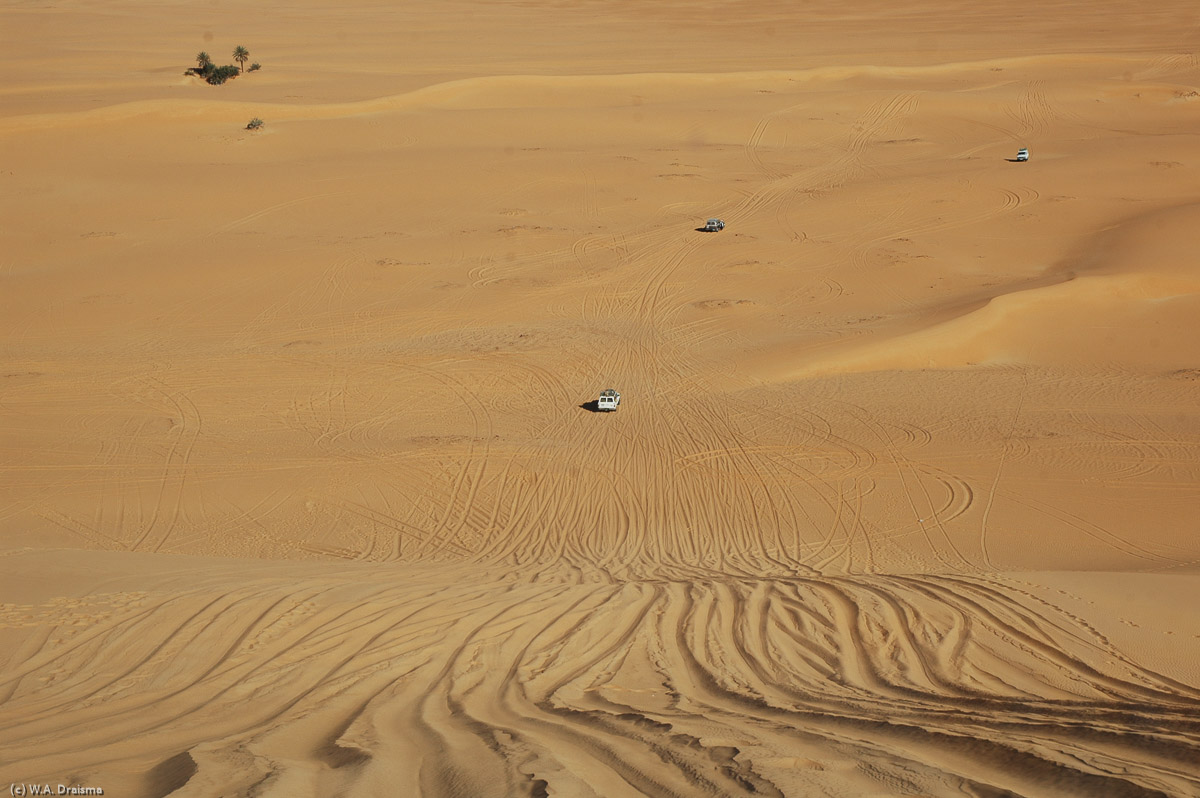 Three cars have safely reached the base of the dune. Now it's our turn. We slowly drive forward gaining speed as we go down the slope. In a very controlled way our driver steers our 4WD towards the waiting cars below. Soon we safely reach the base as well and look back at the others still waiting to drive down.