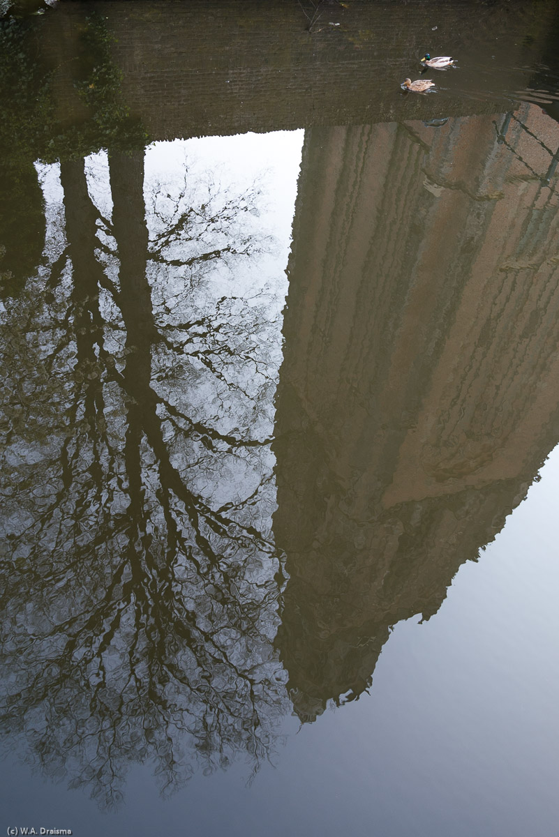 The Onze Lieve Vrouwetoren (Tower of Our Lady) mirrored in the surface of the Westsingel.
